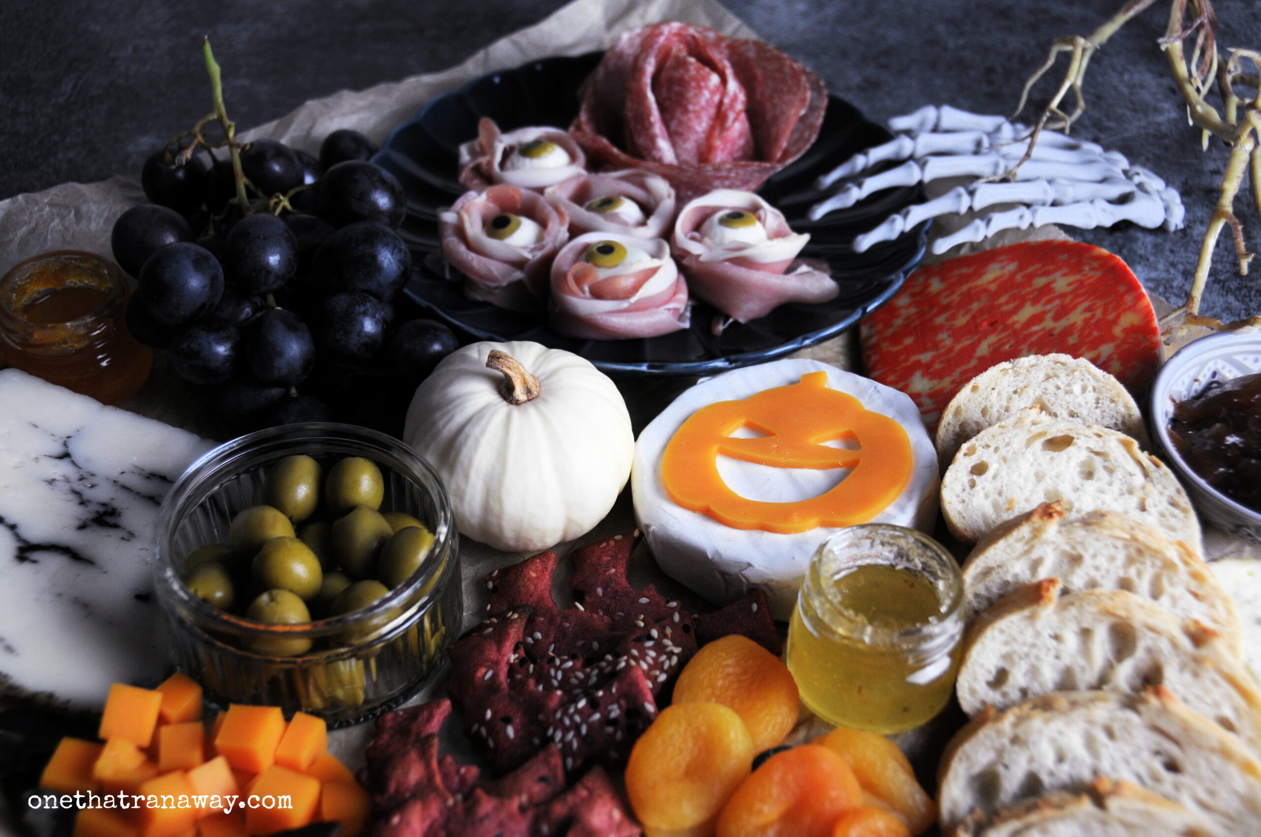 a Halloween themed cheese platter with mozzarella eyeballs, bread and bat shaped crackers on a silver platter