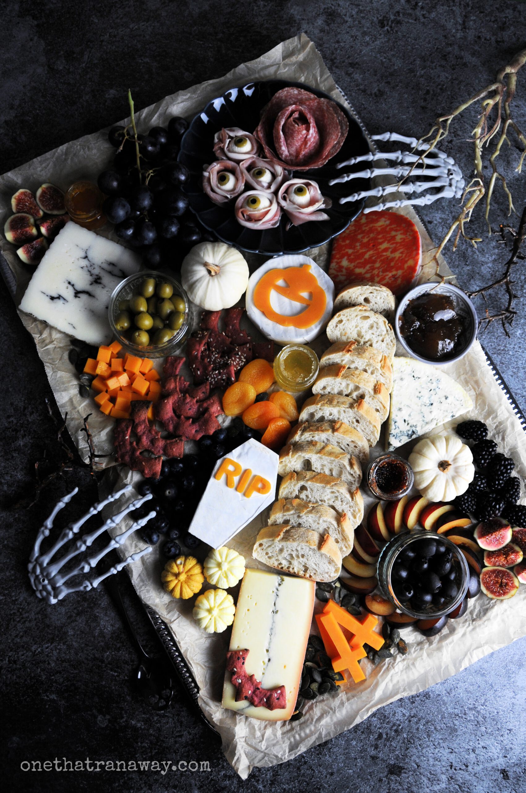 a Halloween themed cheese platter with mozzarella eyeballs, bread and bat shaped crackers on a silver platter