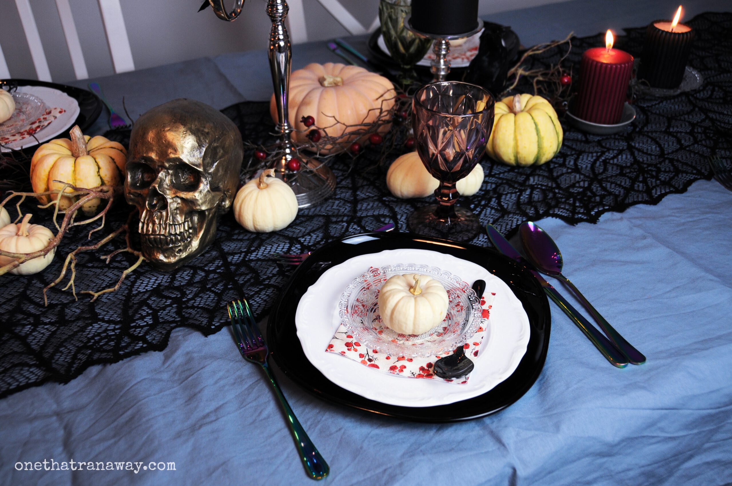 tablescape for a spooky elegant Halloween dinner party with black candles, a black spider web table runner and different pumpkins for decoration
