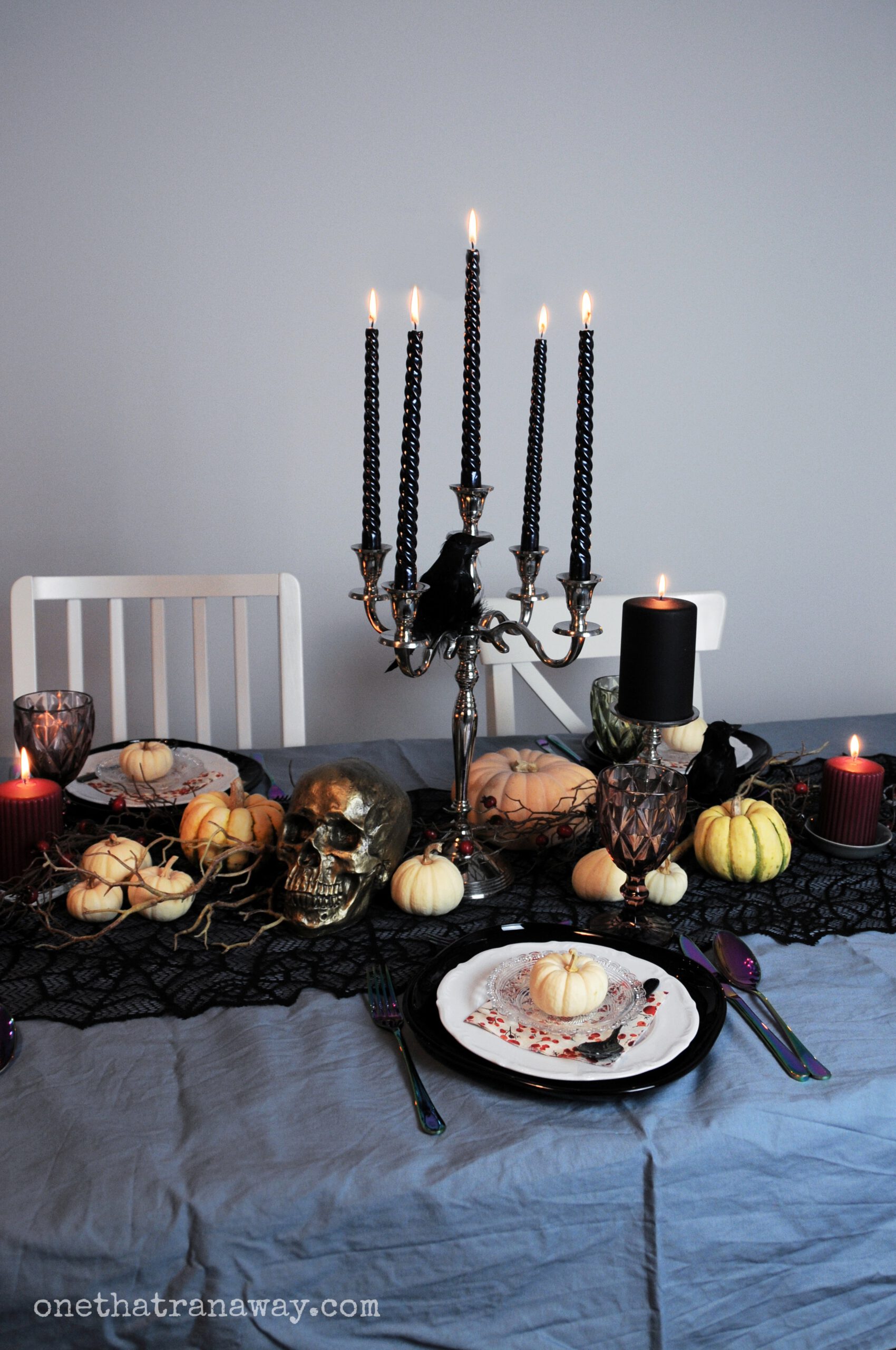 tablescape for a spooky elegant Halloween dinner party with black candles, a black spider web table runner and different pumpkins for decoration