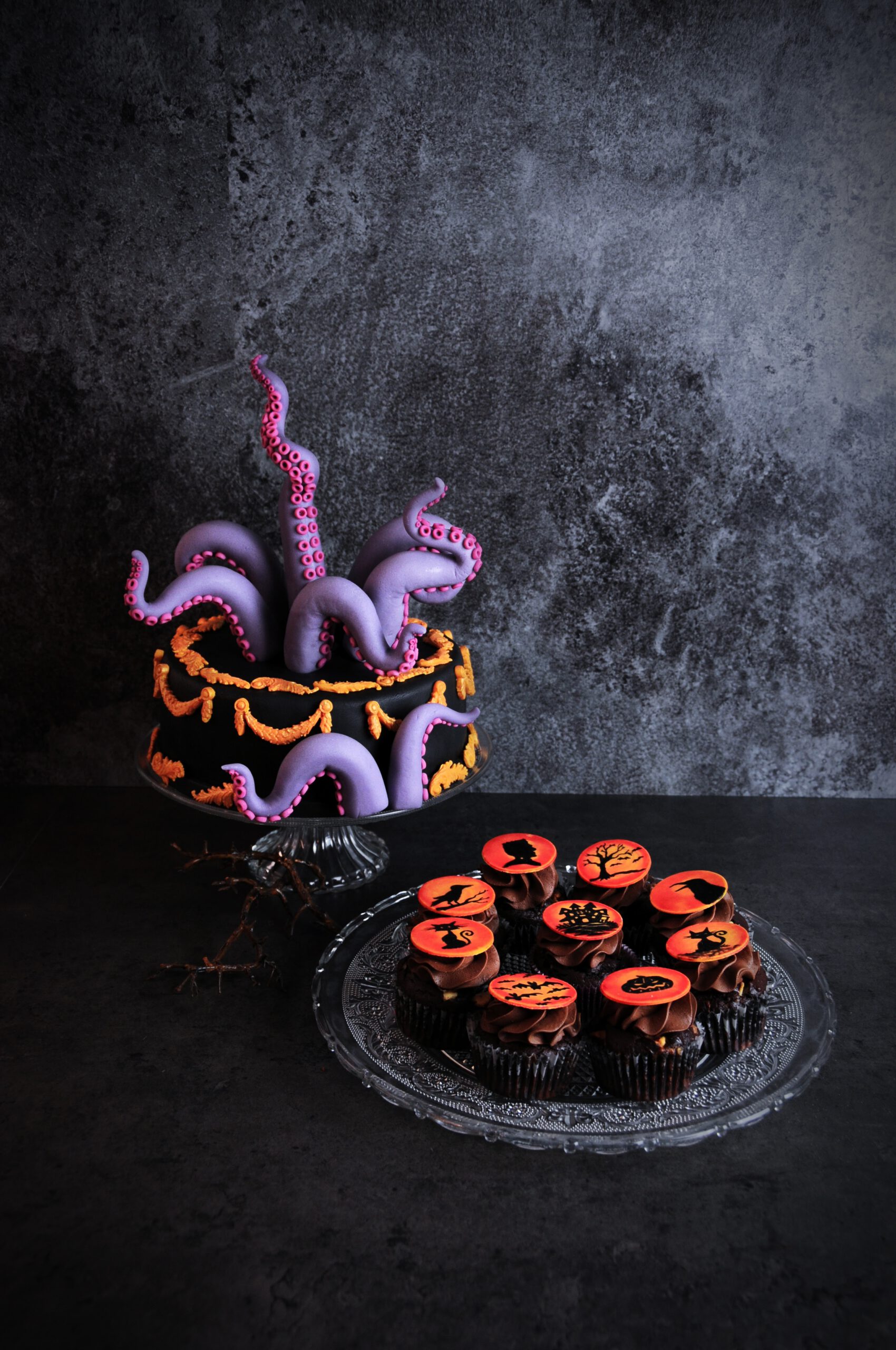 a cake with fondant tentacles and chocolate cupcakes with silhouette fondant cupcake toppers on black background