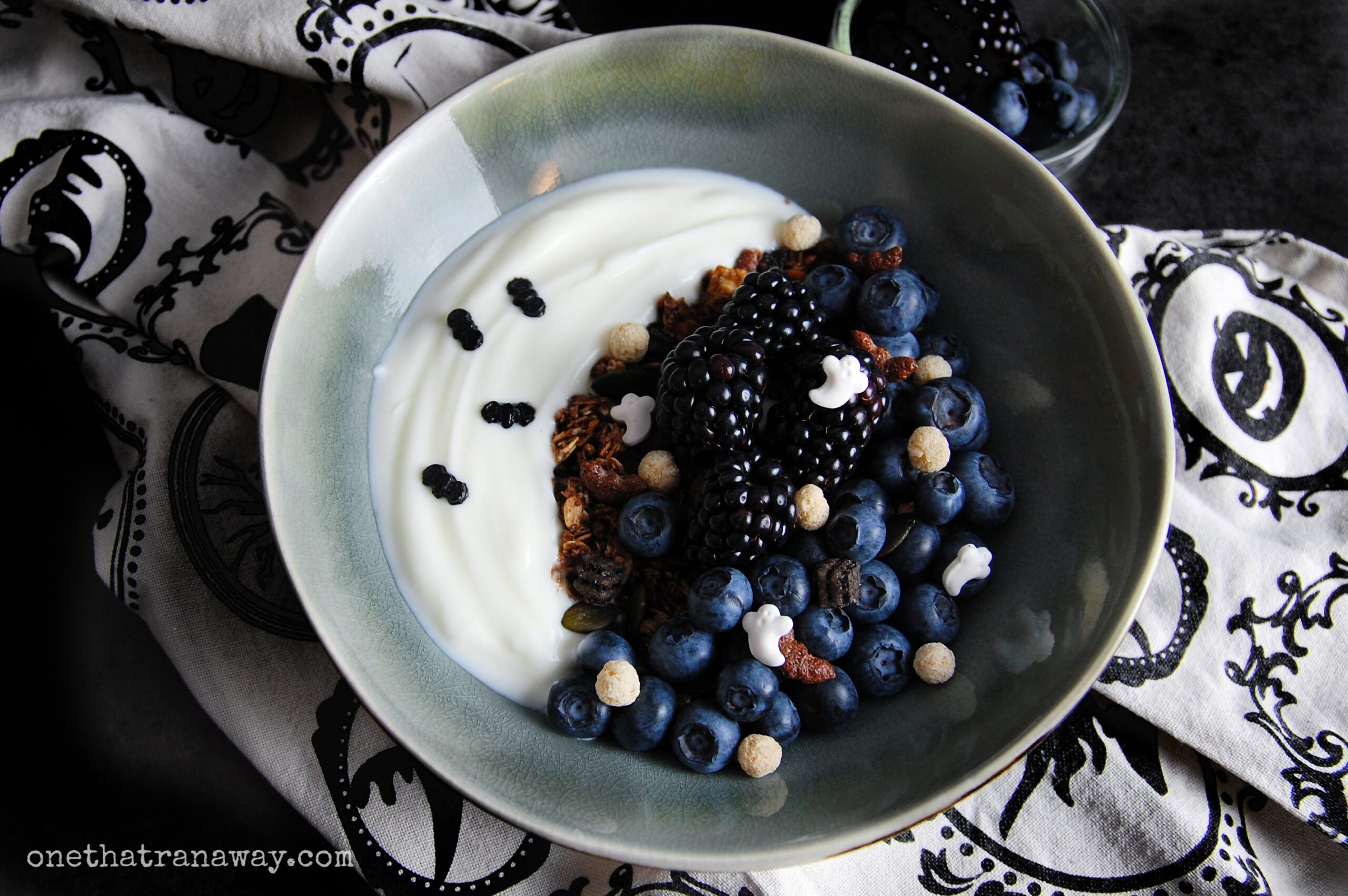 a bowl of yoghurt and cereal forming a crescent moon on top of a beige and black kitchen towel