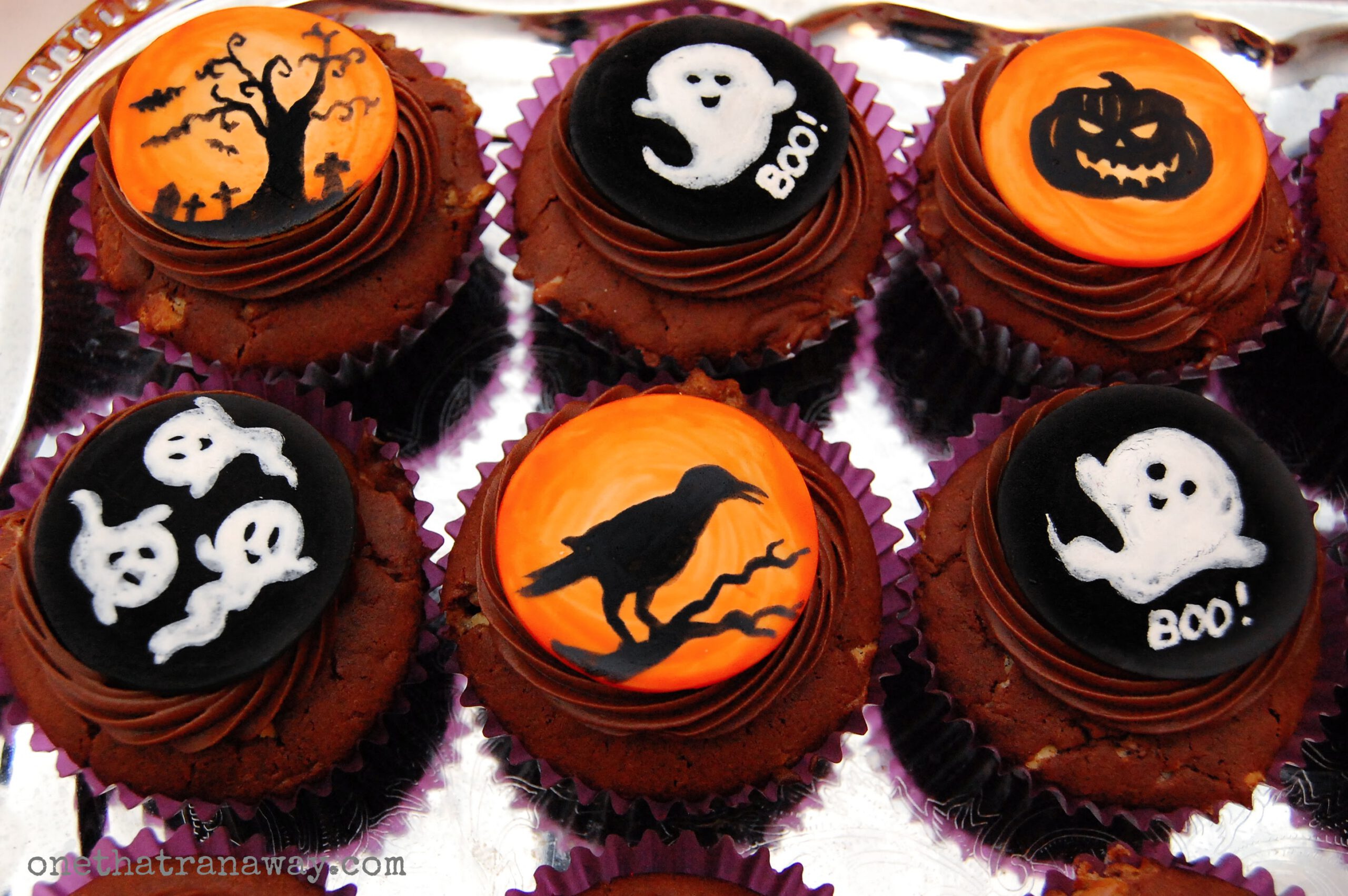 chocolate cupcakes with orange fondant toppers showing Halloween themed silhouettes on silver background