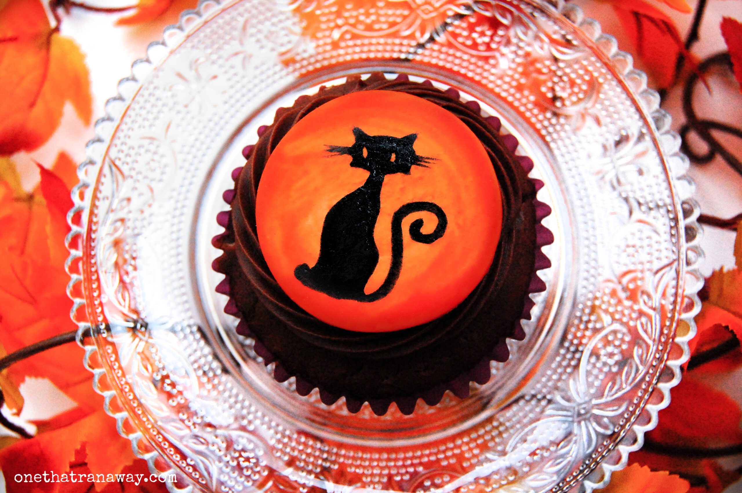 chocolate cupcake with an orange fondant topper showing the silhouette of a cat