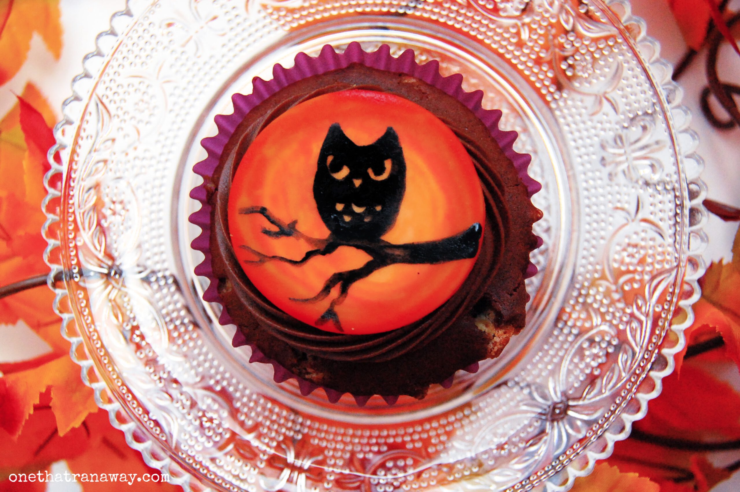 chocolate cupcake with an orange fondant topper showing the silhouette of an owl
