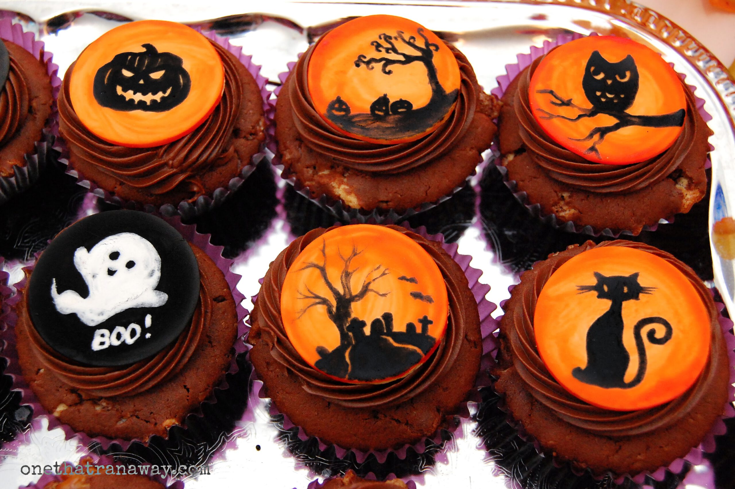 chocolate cupcakes with orange fondant toppers showing Halloween themed silhouettes on silver background